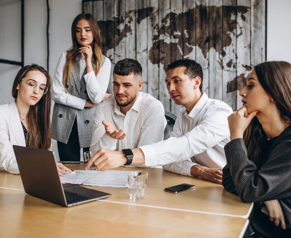 Group of office workers gathered around a laptop discussing business