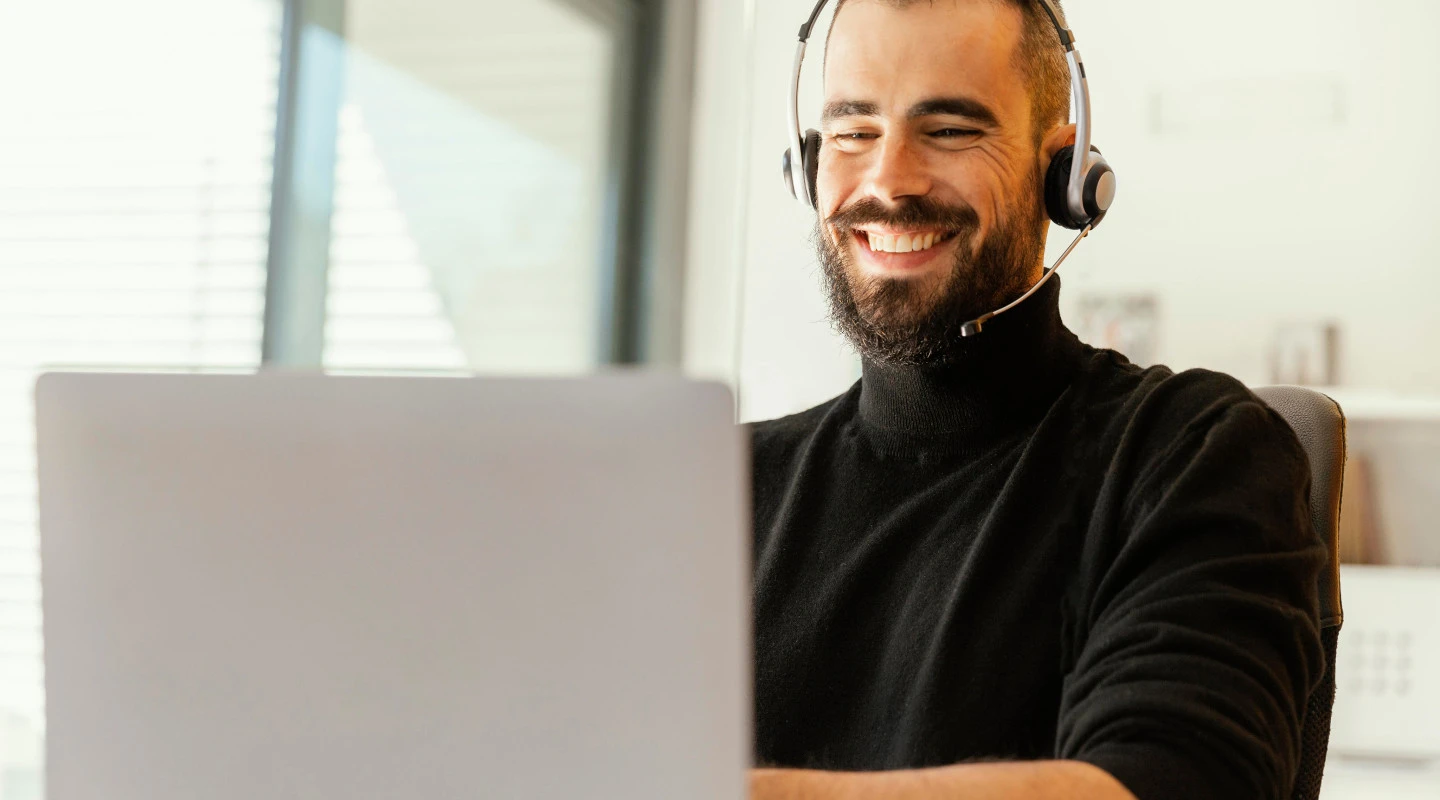 Man wearing a headset on a voice call at a laptop